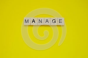 Word manage. Top view of wooden blocks with letters on yellow surface