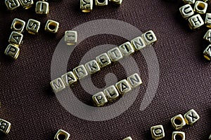 Word MARKETING PLAN made from small golden letters on the brown