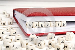 Word Marxism written in wooden blocks in red notebook on white w