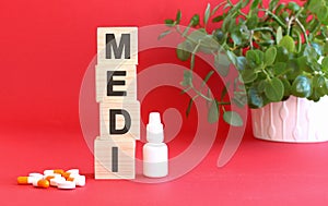 The word MEDI is made of wooden cubes on a red background. Medical concept