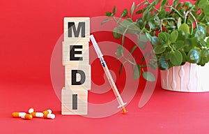 The word MEDI is made of wooden cubes on a red background. Medical concept