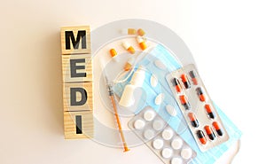 The word MEDI is made of wooden cubes on a white background. Medical concept