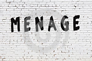 Word menage painted on white brick wall