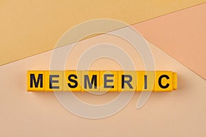 Word mesmeric written on plastic blocks on color background. photo