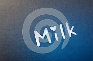 Word `milk` with a heart above the letter i. Love of milk.