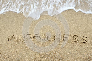 The word Mindfulness written on sand