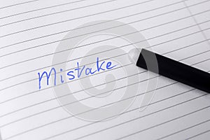 Word Mistake written with erasable pen on lined sheet of paper, closeup