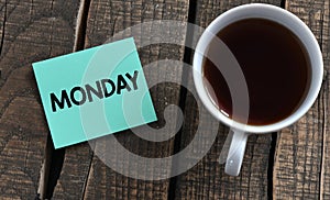 The word MONDAY on a small piece of paper and a wooden table