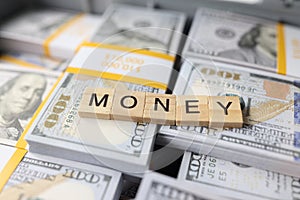 Word money collected from wooden bars on stacks of dollars close-up.