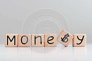 Word MONEY is made of wooden building blocks lying on the table and on a light background.