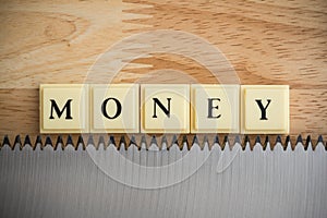 Word MONEY on saw blade with wooden table background macro shot. Money management in business financial on risk or economic crisis