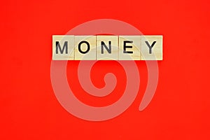 Word money. Top view of wooden blocks with letters on red surface