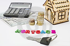 Word Mortgage and wooden house, calculator, money and keys. A loan form with a pledge. Buying real estate or housing on credit. Mo