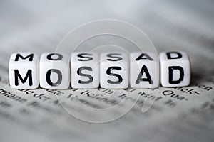 Word MOSSAD formed by wood alphabet blocks on newspaper