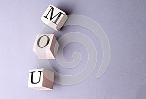 Word MOU on wooden block on the grey background