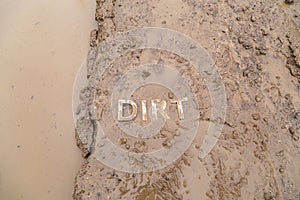 The word mud imprinted in wet dirt road surface - close-up with selective focus