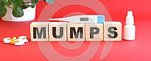 The word MUMPS is made of wooden cubes on a red background. Medical concept