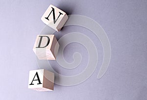 Word NDA on wooden block on the grey background