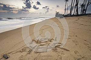 word NEW YEAR written on beach sand over sunset background,