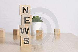 word NEWS with wood building blocks, light green background. front view.