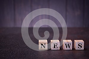 The word news on wooden cubes, on a dark background, light wooden cubes signs, symbols signs