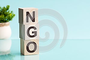 Word NGO - Non-governmental organization - on a wooden cubes on a blue background