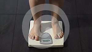 Word Normal written on scales screen, woman on diet measuring weight, healthcare