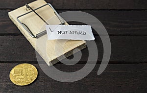 The word: Not afraid pinned on mouse trap with backside of bitcoin.