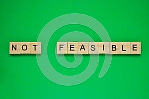 Word not feasible. Top view of wooden blocks with letters on green surface