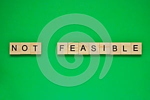 Word not feasible. Top view of wooden blocks with letters on green surface photo