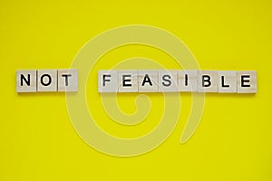Word not feasible. Top view of wooden blocks with letters on yellow surface photo