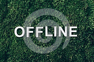 Word Offline on moss, green grass background. Top view. Copy space. Banner. Biophilia concept. Nature backdrop