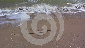 Word OKEAN writing on sand beach.