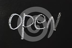 Word open written in white chalk on a black chalkboard