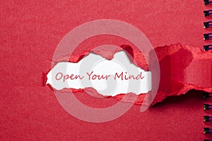 The word open your mind appearing behind torn paper