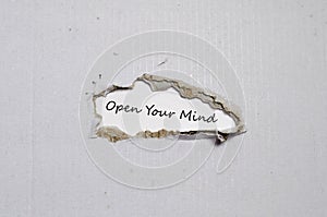 The word open your mind appearing behind torn paper