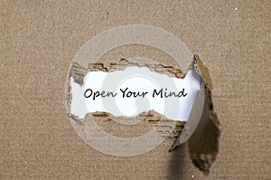 The word open your mind appearing behind torn paper