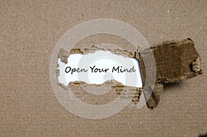 The word open your mind appearing behind torn paper