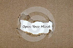 The word open your mind appearing behind torn paper