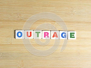 Word Outrage on wood background