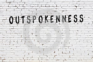 Word outspokenness painted on white brick wall