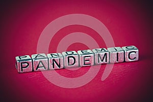 Word pandemic written with metal cubes on white background