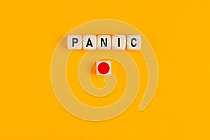 The word panic written on wooden cubes with a red push button. Panic button concept