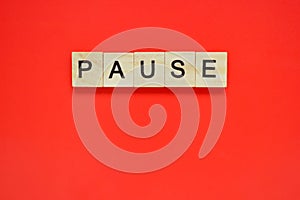 Word pause. Top view of wooden blocks with letters on red surface