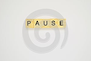 Word pause. Top view of wooden blocks with letters on white surface