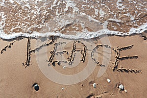 The word `Peace` on the sea sand, written with stick on the beach.
