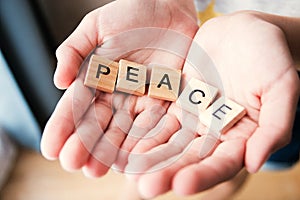 The word Peace is written in cubic letters in hands, selective focus