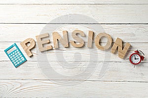 Word Pension, calculator and alarm clock on wooden background