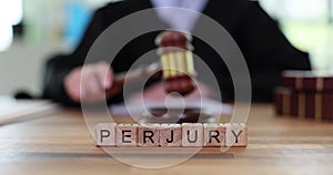 Word Perjury made of wooden cubes against judge with gavel