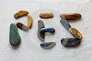 Word PEZ is written using colored stones on a white grainy surface
Translation: fish photo